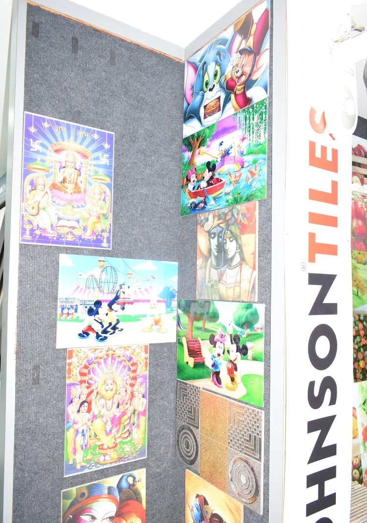 Printed tile panels on the Johnson Tiles stand — deity prints alongside cartoon designs for children's rooms