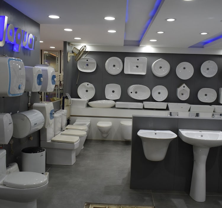 Grid of wall-mounted wash basins under the lit Jaquar sign, with pedestal basins and water closets on the floor