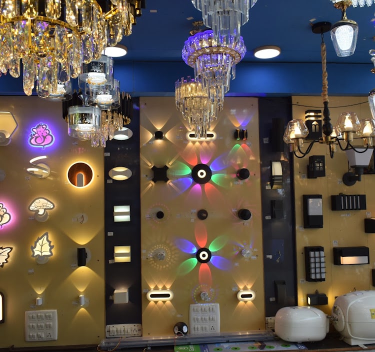 Wall of LED wall lights, colour-changing fixtures and figurative lamps lit under crystal chandeliers