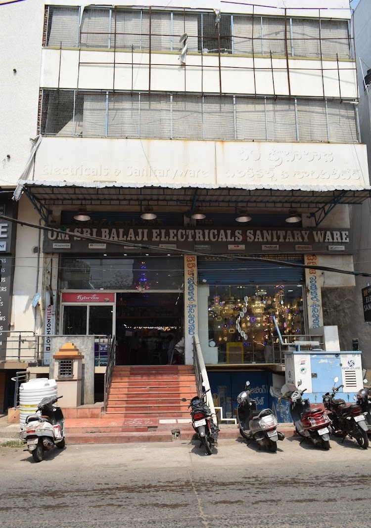 Street view of the shop entrance with the OM SRI BALAJI ELECTRICALS SANITARY WARE signboard and steps up from the road