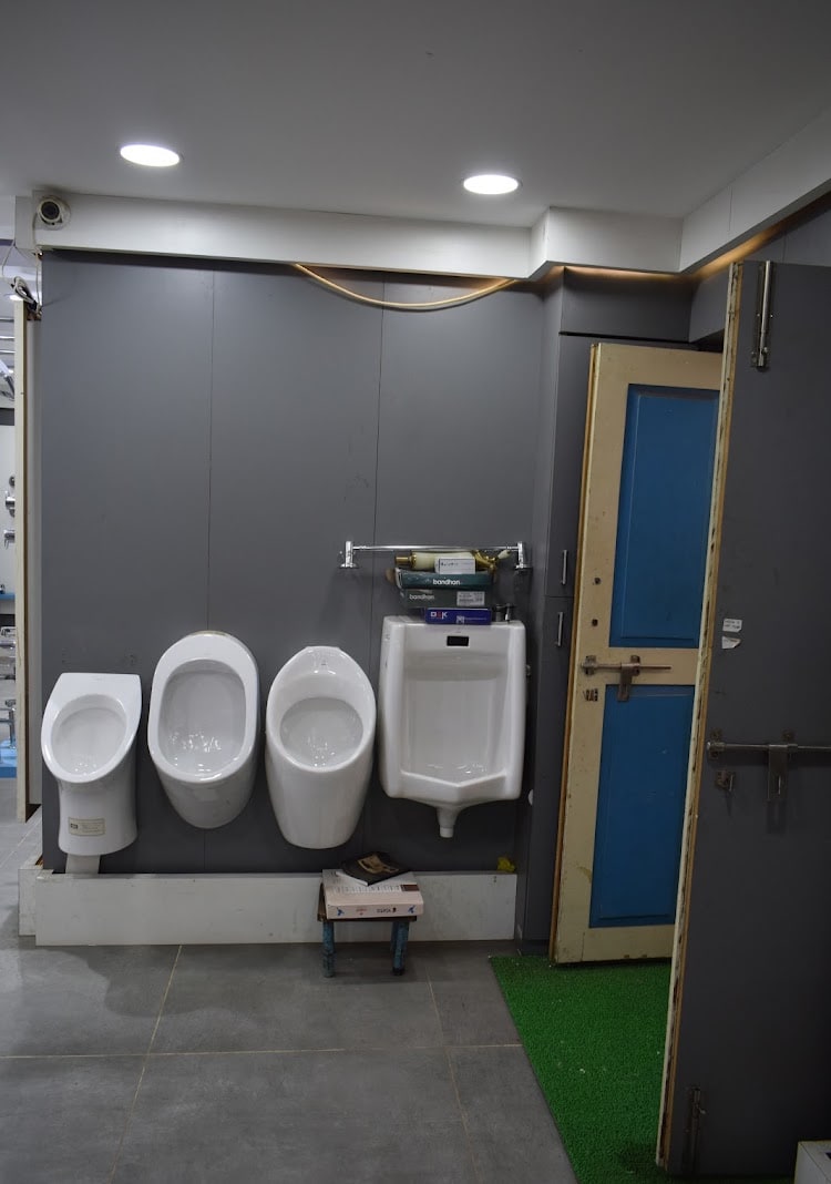 Four wall-mounted urinals in different sizes fixed along the grey display panel